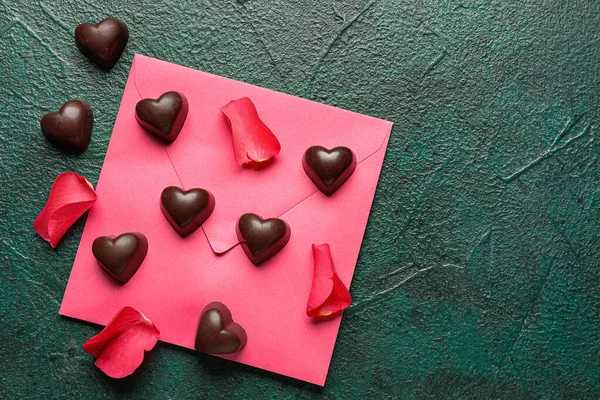 Komposition Mit Leckeren Schokoladenbonbons Rosenblättern Und Umschlag Auf Grünem Hintergrund — Stockfoto