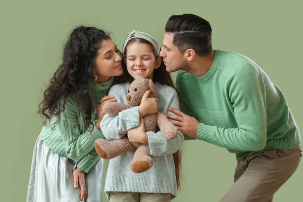 快乐的父母在绿色背景下亲吻他们的小女儿 — 图库照片