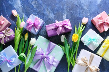 Mavi arka planda Uluslararası Kadınlar Günü için güzel lale çiçekleri ve hediye kutuları