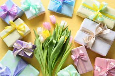 Sarı zemin üzerinde Uluslararası Kadınlar Günü için güzel lale çiçekleri ve hediye kutuları