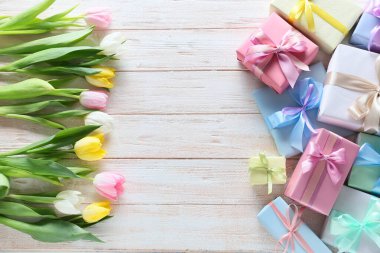 Uluslararası Kadınlar Günü için açık ahşap arka planda hediye kutlaması ve çiçeklerle birlikte kompozisyon