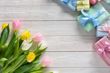 Uluslararası Kadınlar Günü için açık ahşap arka planda hediye kutlaması ve çiçeklerle birlikte kompozisyon