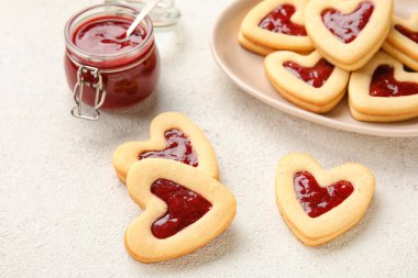 Sevgililer Günü kutlamaları için tatlı kurabiyeler ve reçelli tabaklar arka planda, yakın plan.