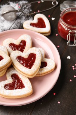 Koyu ahşap arka planda Sevgililer Günü kutlaması için lezzetli kurabiyeler ve reçel. Yakın plan.