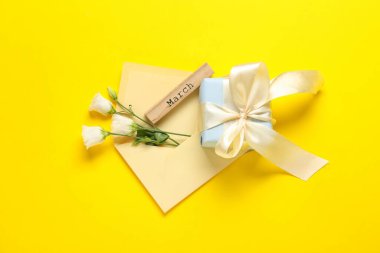 Zarflı kompozisyon, Eustoma çiçekleri, hediye kutusu ve sarı arka planda marş.