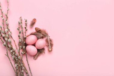 Composition with beautiful Easter eggs, feathers and pussy willow branches on pink background
