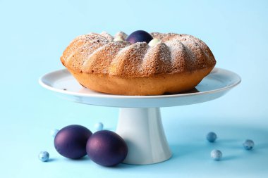 Tatlı standında lezzetli Paskalya pastası ve mavi arka planda yumurtalar.