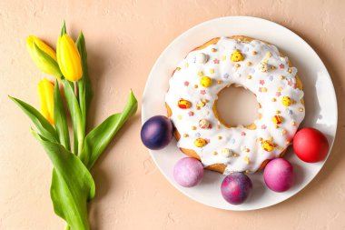 Lezzetli Paskalya pastası, lale çiçekleri ve bej arka planda yumurtalar.