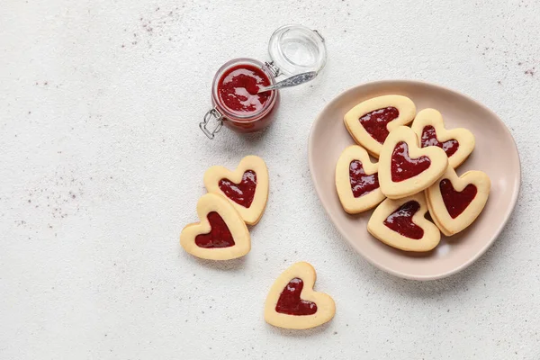 薄い背景にバレンタインデーのお祝いのためのおいしいクッキーとジャムとプレート — ストック写真