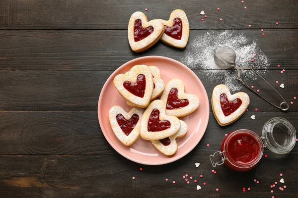 暗い木製の背景にバレンタインデーのお祝いのためのおいしいクッキーとジャムとプレート — ストック写真