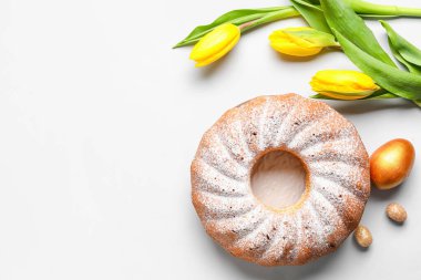 Lezzetli Paskalya pastası, lale çiçekleri ve açık arkaplanda yumurtalar.