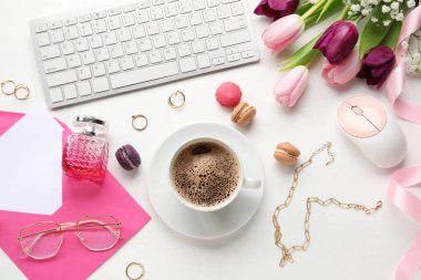 Klavyeli kompozisyon, bilgisayar faresi, bir fincan kahve, kadın aksesuarları ve açık arkaplanda güzel çiçekler