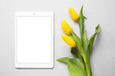 Tablet bilgisayar ve çiçek buketi açık arkaplanda