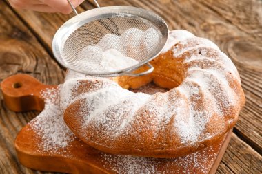 Tahta zemindeki Paskalya pastasına şeker tozu ekliyorum.