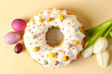 Lezzetli Paskalya pastası, bej arka planda yumurta ve lale çiçekleri.