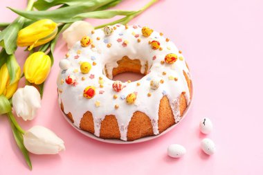 Lezzetli Paskalya pastası ve pembe arka planda lale çiçekleri.