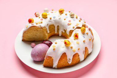 Lezzetli Paskalya pastası ve pembe arka planda yumurta tabağı.