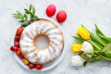 Lezzetli Paskalya pastası, lale çiçekleri ve açık arkaplanda yumurtalar.