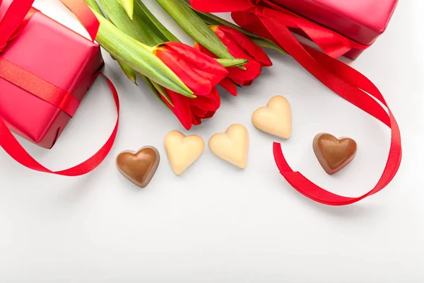 Kalp Şeklinde Lezzetli Çikolata Şekerler Beyaz Arka Planda Kırmızı Laleler — Stok fotoğraf