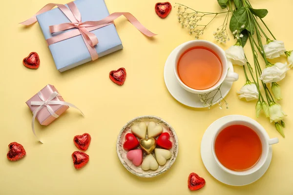 ベージュを背景にバレンタインデーのお祝いのためのおいしいハート型のキャンディー 花やお茶のカップと構成 — ストック写真