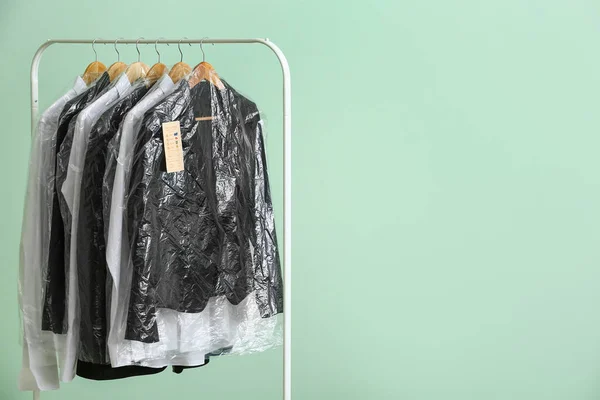 Rack Met Schone Jassen Shirts Plastic Zakken Groene Achtergrond — Stockfoto