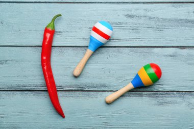 Mavi ahşap arka planda acı biber ve Meksika marakası.