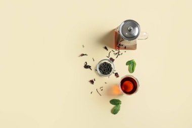 Çaydanlık ve bardağın karışımı, sarı arka planda lezzetli çay.