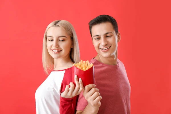 Pareja Joven Con Papas Fritas Sobre Fondo Rojo —  Fotos de Stock