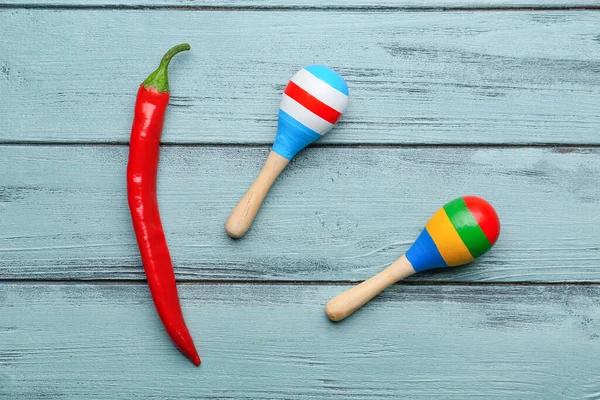 Mavi ahşap arka planda acı biber ve Meksika marakası.