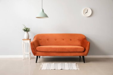 Şık kahverengi kanepe ve vazo, ışık duvarının yanında.