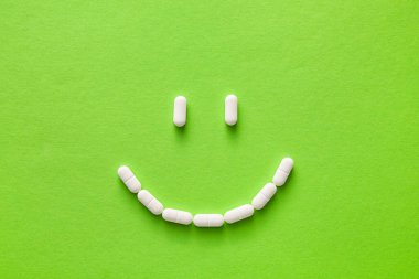 Arka planda beyaz haplardan yapılmış gülümseme