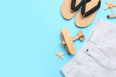 Ahşap düzlemli kompozisyon, renk arkaplanındaki parmak arası terlikler ve şortlar