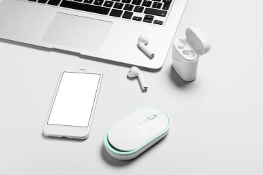 Beyaz arkaplanda cep telefonu, dizüstü bilgisayar, kulaklık ve bilgisayar faresi