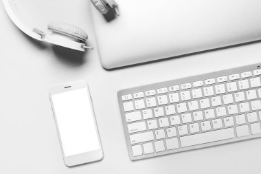 Cep telefonu, klavye, dizüstü bilgisayar ve kulaklıklar beyaz arkaplanda, yakın plan