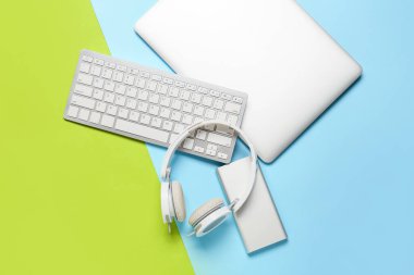 Renkli arka planda modern dizüstü bilgisayar, klavye, kulaklık ve güç bankası