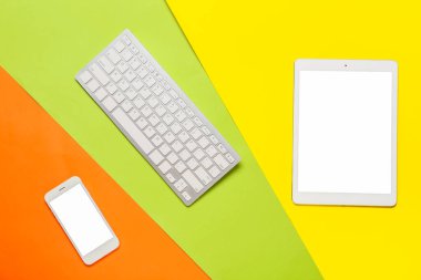 Renk arkaplanındaki tablet bilgisayarı, cep telefonu ve klavye