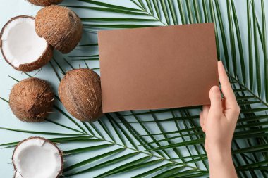Boş kartı, hindistan cevizi ve palmiye yaprakları olan kadın eli