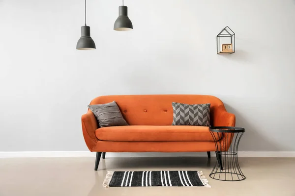 ライトウォールの近くに枕とテーブル付きのスタイリッシュな茶色のソファ — ストック写真