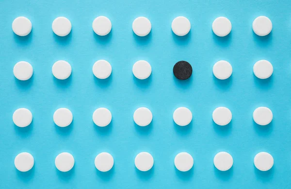 Μαύρο Χάπι Μεταξύ Των Λευκών Μπλε Φόντο Έννοια Της Μοναδικότητας — Φωτογραφία Αρχείου