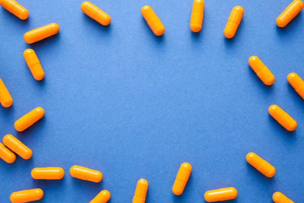 Frame made of capsules on blue background