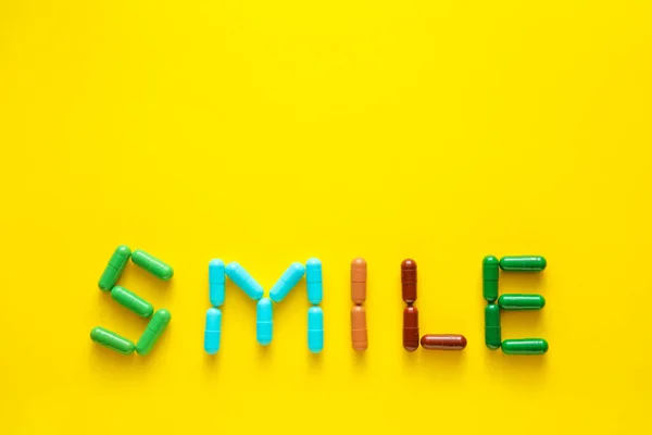 Word Smile Hecho Cápsulas Sobre Fondo Amarillo — Foto de Stock