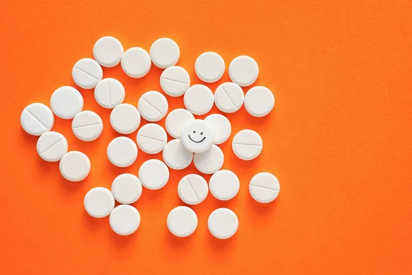 One pill with drawn happy face among ones on color background
