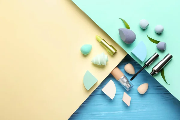 Composition with different makeup sponges and cosmetics on color background