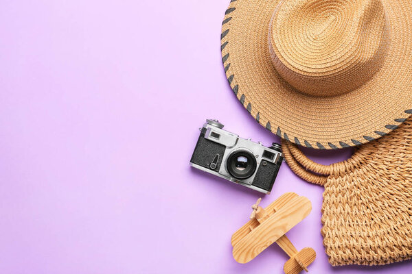 Stylish hat, bag, photo camera and wooden plane on color background