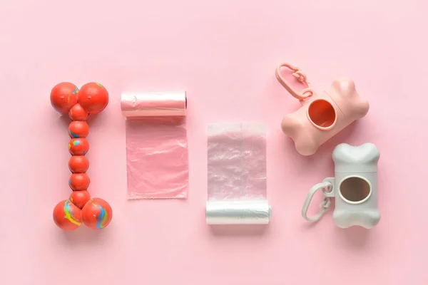 Dispensers with pet waste bags and toy on pink background