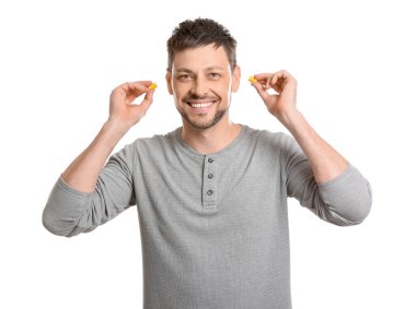 Beyaz arka planda sarı kulak tıkacı olan yakışıklı bir adam.