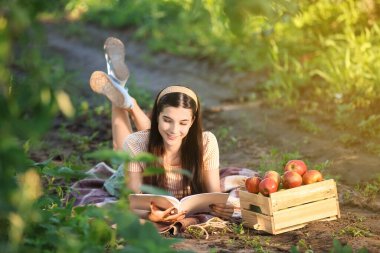 Yaz günü bahçede kitap okuyan güzel genç bir kadın.