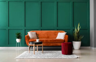 Renk duvarının yanında rahat puf ve kanepesi olan modern oturma odasının içinde.