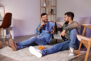 Bira şişeleri olan küçük kardeşler akşamları evde video oyunu oynuyorlar.