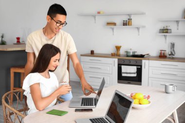 Bir fincan çayla genç bir kadın ve erkek arkadaşı mutfaktaki otel odasında rezervasyon yaptırıyor.